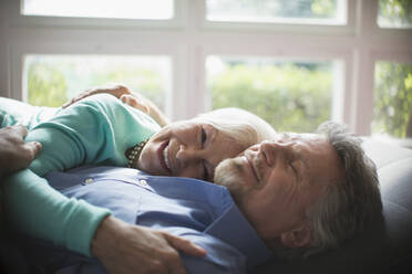 Happy senior couple cuddling by sunny window - CAIF29835