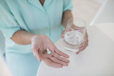 Ältere Frau, die Vitamine mit Wasser einnimmt - CAIF29858