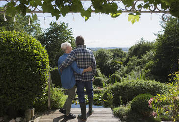 Zärtliches Seniorenpaar umarmt sich auf sonniger Sommergarten-Terrasse - CAIF29865