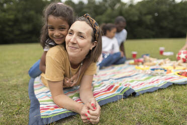 Portrait happy mother and daughter relaxing on picnic blanket in park - CAIF29928