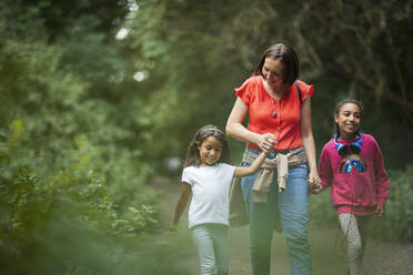 Mother and daughters hiking on trail in woods - CAIF29930