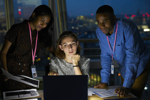 Business people working late at laptop in office - CAIF29961