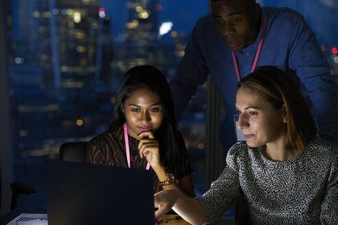 Business people working late at laptop in office - CAIF29972