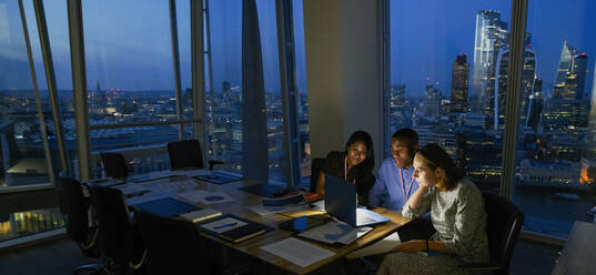 Business people working late at laptop in highrise office, London, UK - CAIF29974