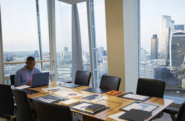 Businessman working at laptop in highrise conference room, London, UK - CAIF29981