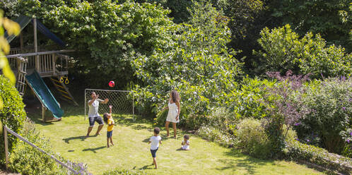 Familie spielt Fussball im sonnigen Sommerhinterhof - CAIF29991