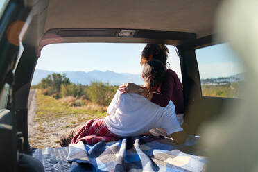 Zärtliches junges Paar genießt sonnige Aussicht auf die Natur vom Heck des Autos - CAIF30005
