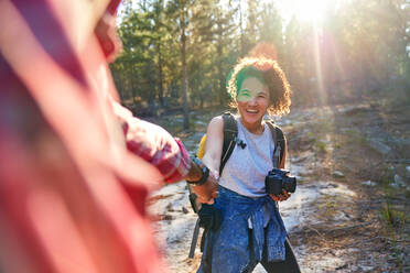 Glückliches junges Paar wandert mit der Kamera in sonnigen Wäldern - CAIF30006