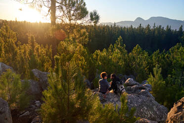 Junges Wanderpaar entspannt sich auf Felsen in sonnigen Wäldern - CAIF30011