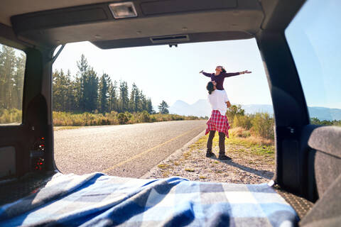 Carefree young couple outside car at sunny remote roadside stock photo