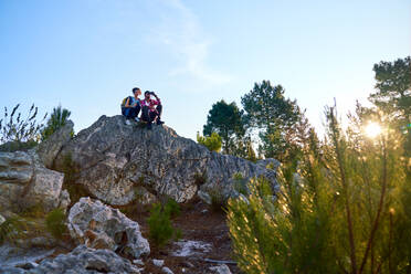 Junges Wanderpaar entspannt sich auf Felsen in sonniger Natur - CAIF30016