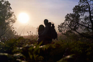 Silhouette eines ruhigen jungen Paares, das den Sonnenuntergang in der Natur genießt - CAIF30040