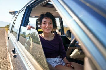 Glückliche junge Frau genießt Autoreise im Auto - CAIF30043