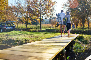 Barefoot young couple walking on sunny autumn lakeside dock - CAIF30046