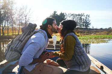 Zärtliches junges Paar küsst sich im Ruderboot auf einem sonnigen Herbstsee - CAIF30061