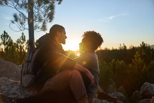 Liebenswertes junges Wanderpaar genießt ruhigen Sonnenuntergang im Wald - CAIF30066