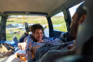 Happy young couple relaxing and camping inside back of car - CAIF30071