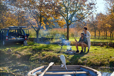 Happy young couple fishing at sunny autumn riverside - CAIF30077