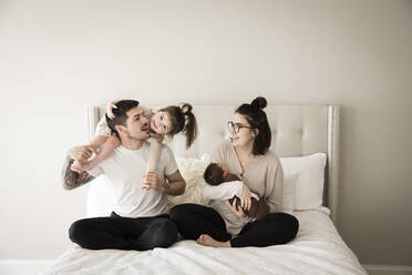 Happy Millennial Family Plays Together on Bed - CAVF90140