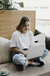 Woman concentrating while using laptop sitting on sofa - LHPF01319