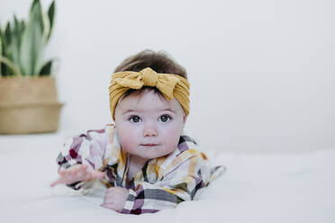 Baby-Mädchen trägt Kopfbogen spielen, während auf dem Bett zu Hause liegen - EBBF01062