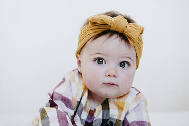 Baby-Mädchen mit Stirnband starrt, während auf dem Bett zu Hause liegen - EBBF01064