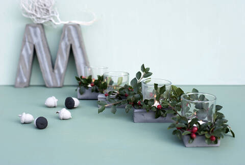 Concrete letter M, painted acorns and candles inside glasses decorated with twigs of cotoneaster stock photo