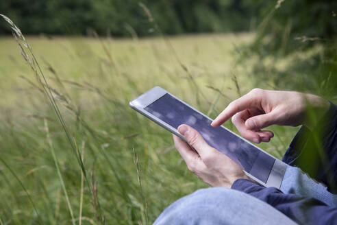 Älterer Mann, der ein digitales Tablet benutzt, während er in der Natur sitzt - MAMF01379