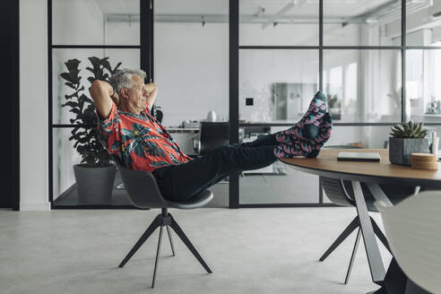 Businessman with hands behind hand relaxing on chair at office - GUSF04500