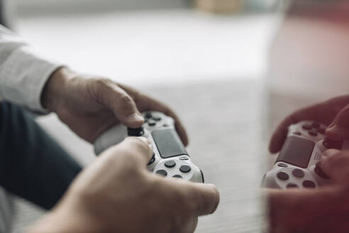 Businessman hands holding video game remote control at office - GUSF04503