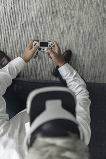 Businessman wearing virtual reality eyeglasses while playing video game at office - GUSF04507