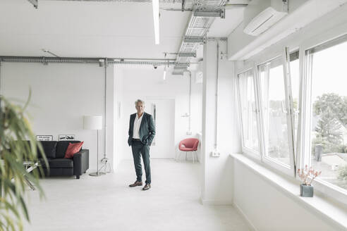 Businessman with hands in pockets standing at new office - GUSF04509