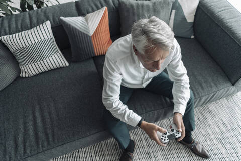 Businessman playing video game while sitting on sofa at office stock photo