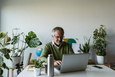 Älterer Mann mit Brille arbeitet zu Hause am Laptop - VABF03675