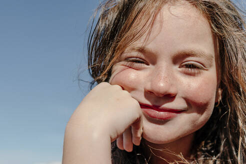 Close-up of girl with hand on chin during sunny day - OGF00606