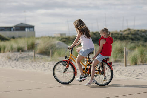 Sisters riding on bicycle during sunny day - OGF00625