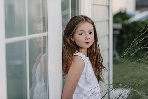 Girl leaning on glass wall during sunny day - OGF00628