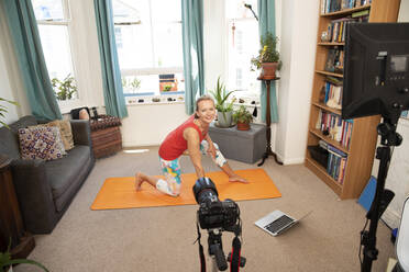 Fitness woman doing exercise video recording with camera at home - PMF01465