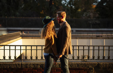 Married couple looking at each other while standing against railing at city - OCMF01794