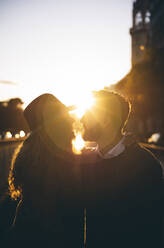 Silhouette of couple standing with arm around in city - OCMF01795