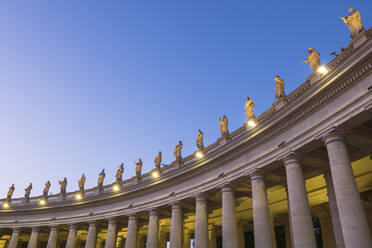 Beleuchtete Heiligenstatuen auf dem Petersdom gegen den klaren blauen Himmel in der Abenddämmerung, Vatikanstadt, Rom, Italien - ABOF00574