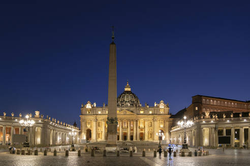 Illuminated St. Peter's Square with obelisk and St. Peter's Basilica against clear blue sky at night, Vatican City, Rome, Italy - ABOF00582