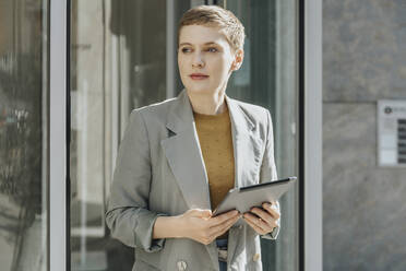 Woman using digital tablet looking away while standing on street in city - MFF06721