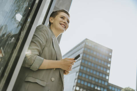 Smiling woman using smart phone while standing on street in city stock photo