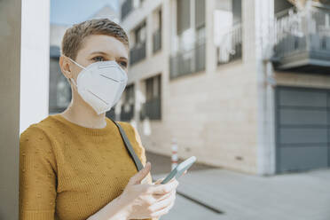 Woman looking away wearing protective face mask using smart during covid-19 - MFF06762