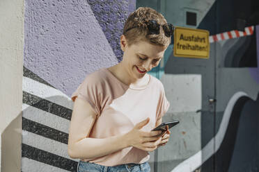 Mid erwachsene Frau Text-Messaging auf Smartphone stehen gegen bunte Wand - MFF06782