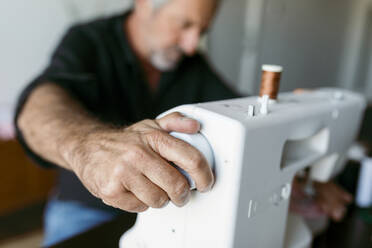 Schneiderin beim Einstellen der Nähmaschine während der Arbeit im Atelier - VABF03700