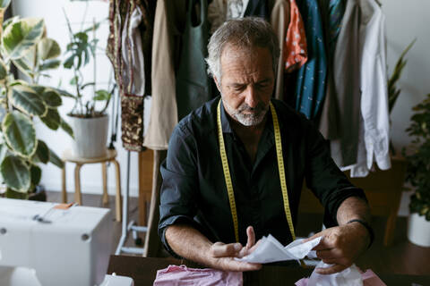 Tailor checking fabric swatch at work studio stock photo