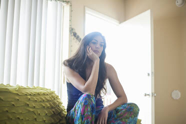 Thoughtful woman with head in hands sitting on sofa at home - AJOF00431