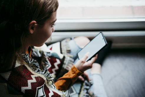 Pre-adolescent girl using mobile phone while sitting at home - EBBF01101